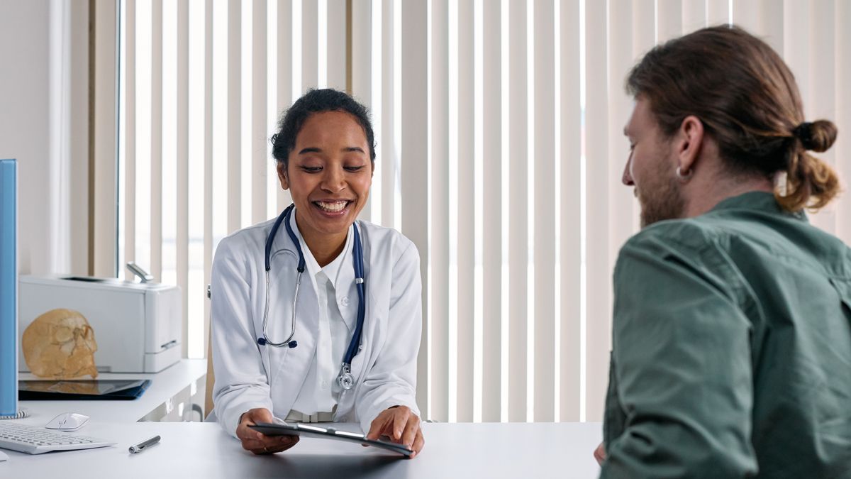 A smiling provider reviewing a tablet with a patient during a consultation