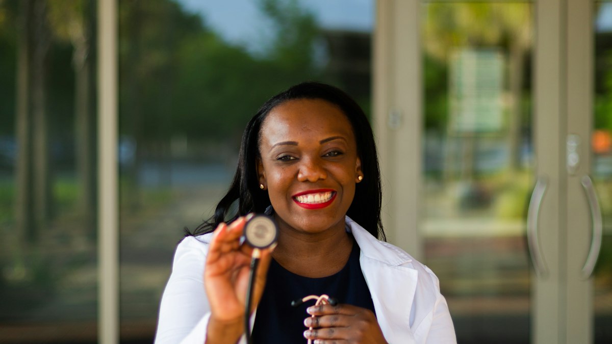 A smiling provider in a white coat holding a stethoscope
